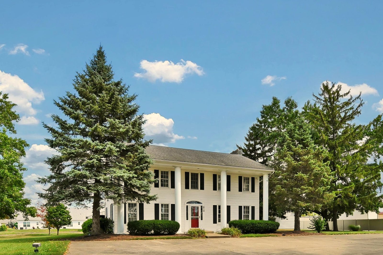 White columned colonial home with a red front door and mature trees at Colonial Retreat in LaGrange, Ohio