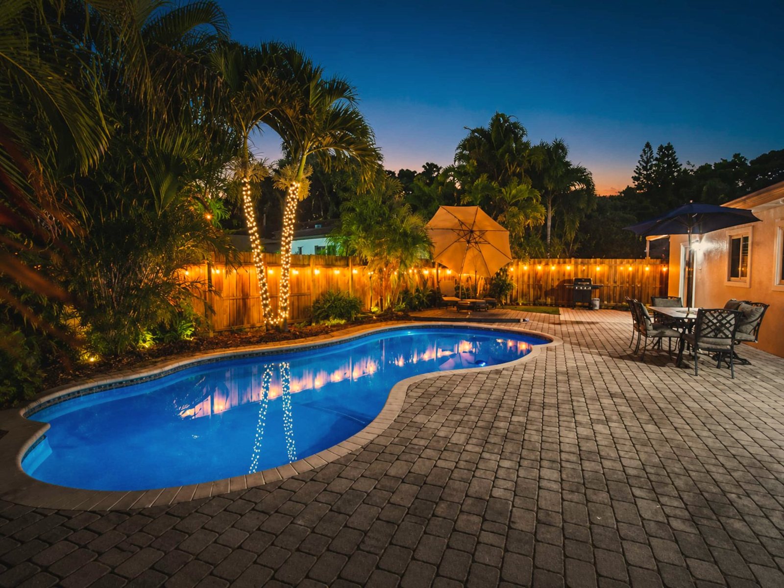 Heated pool lit up at dusk with palm trees and string lights in Fort Lauderdale, Florida
